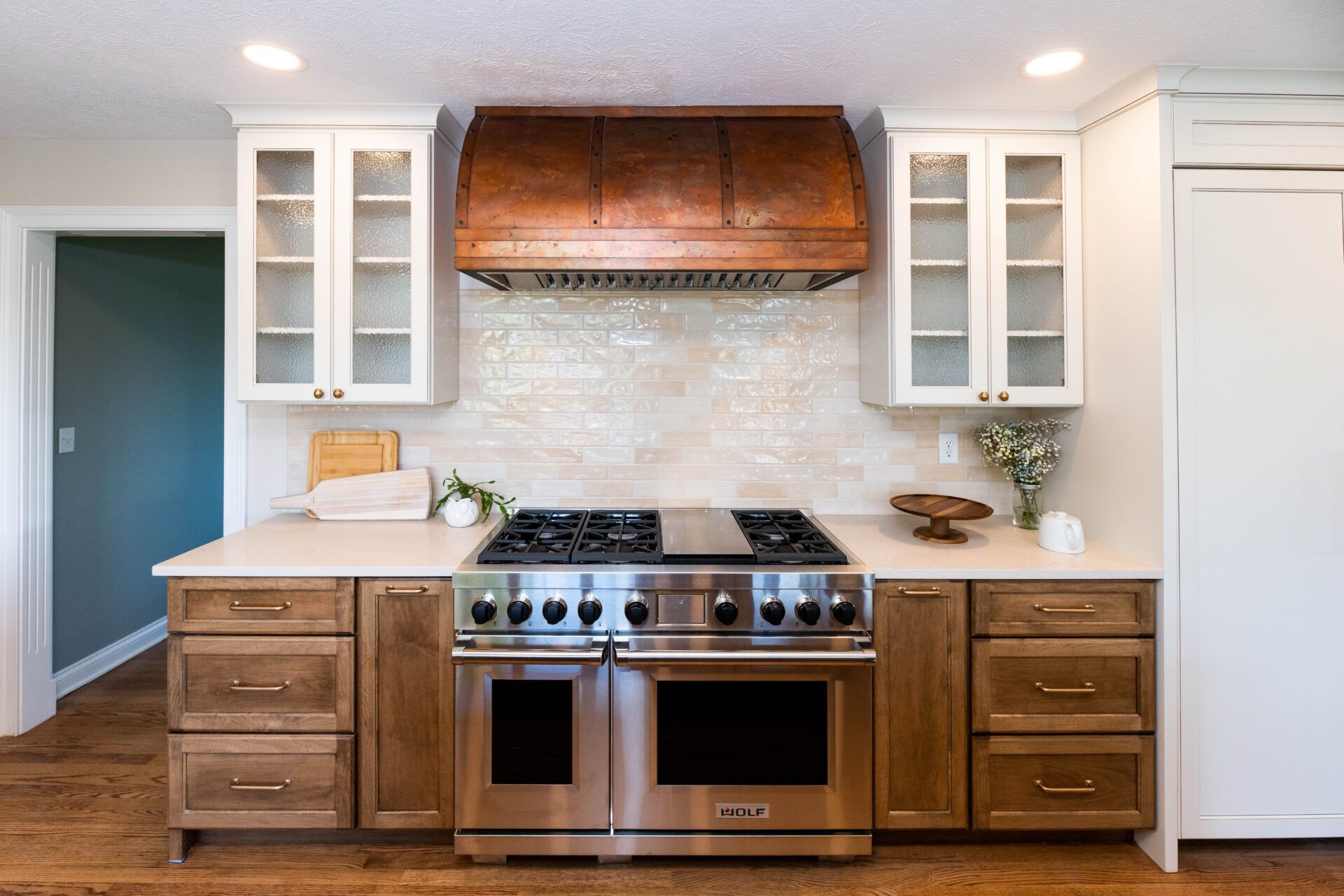 Kitchen with stainless steel range, copper hood, white cabinets, and wood lower cabinets.