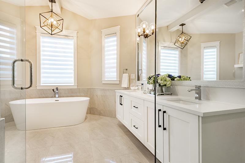 Luxurious bathroom with white cabinets, freestanding tub, and large mirror.