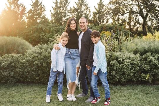 A family is posing for a picture in a park.