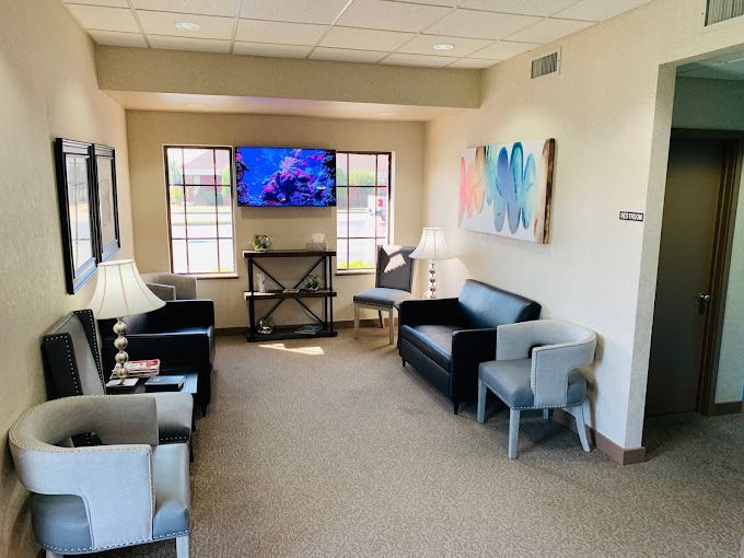 a waiting room with a couch , chairs and a flat screen tv .