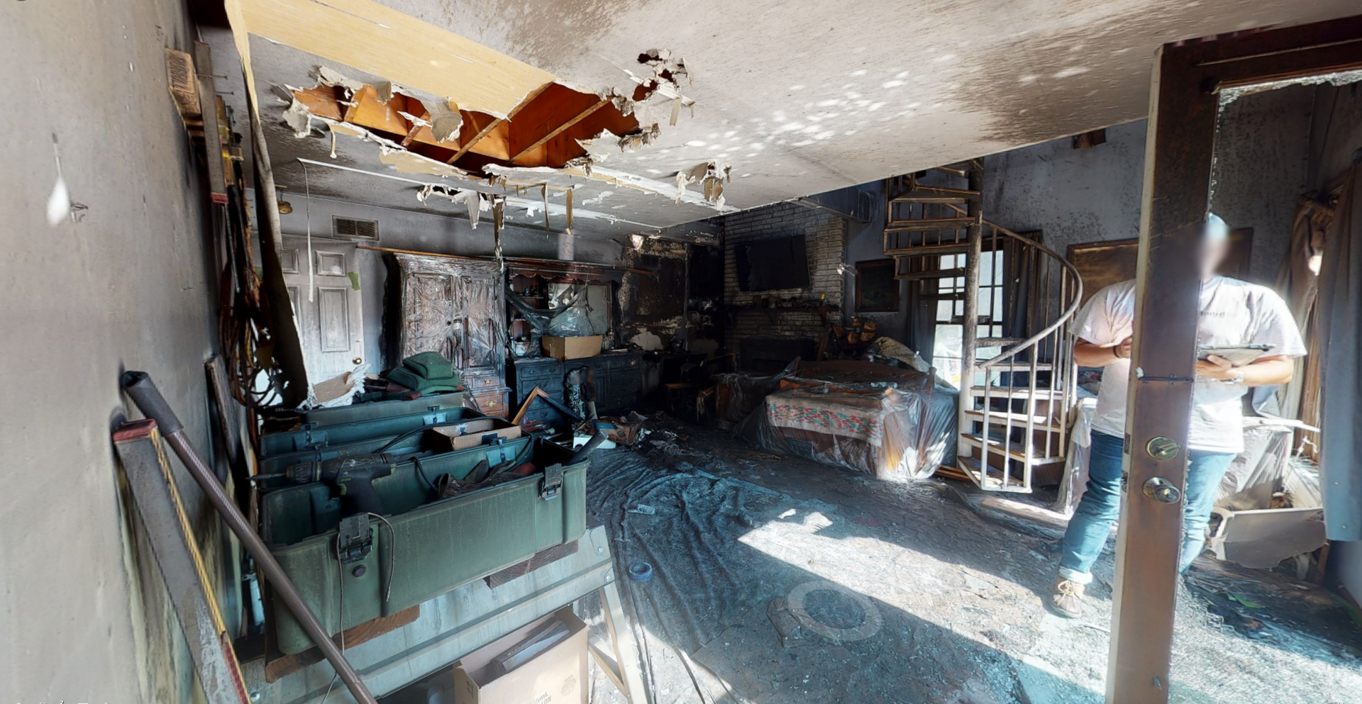 A man is standing in a room with a broken ceiling.