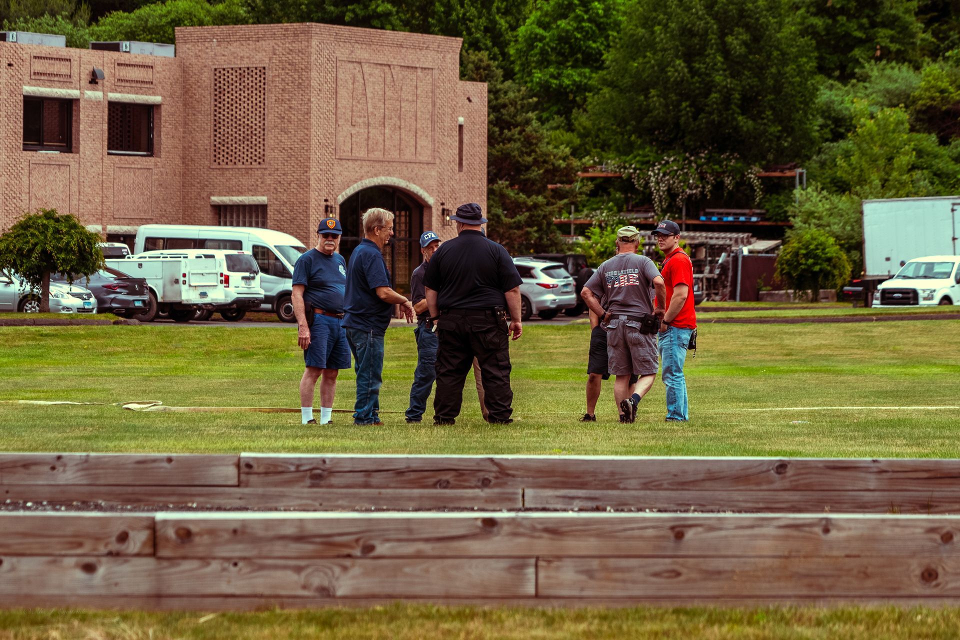 A group of people are standing in a grassy field in front of a building.