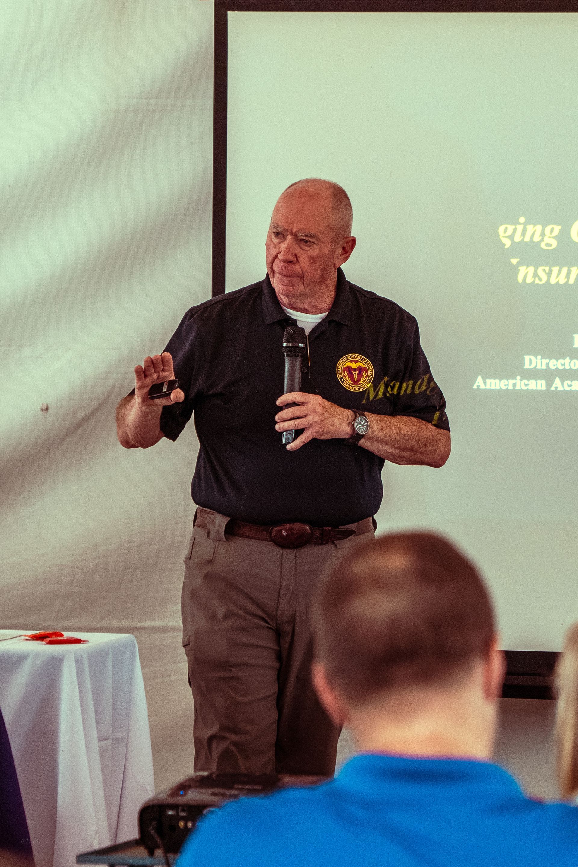 A man in a black shirt is giving a presentation to a group of people