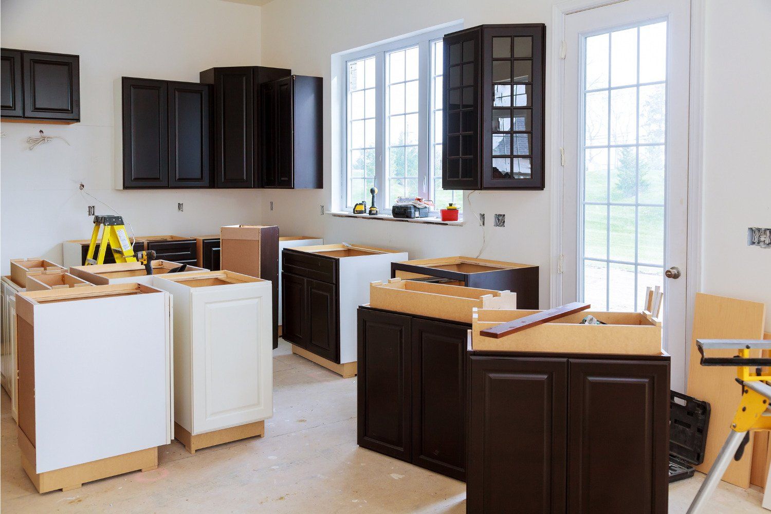 A kitchen is being remodeled with black cabinets and white cabinets.