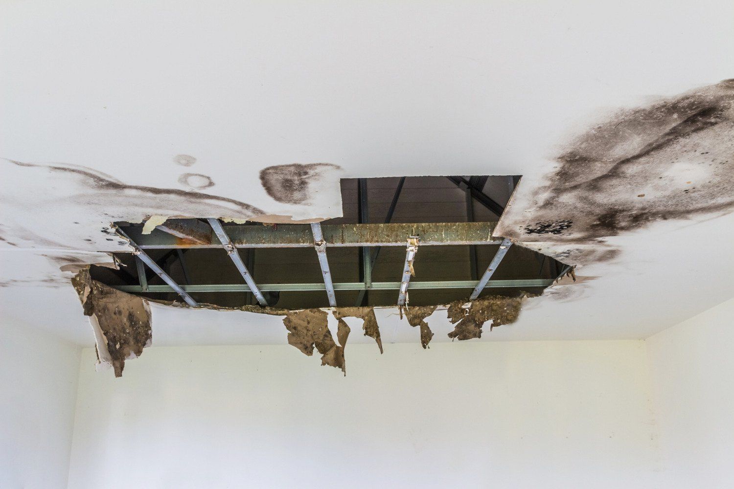 A hole in the ceiling of a room with water damage.