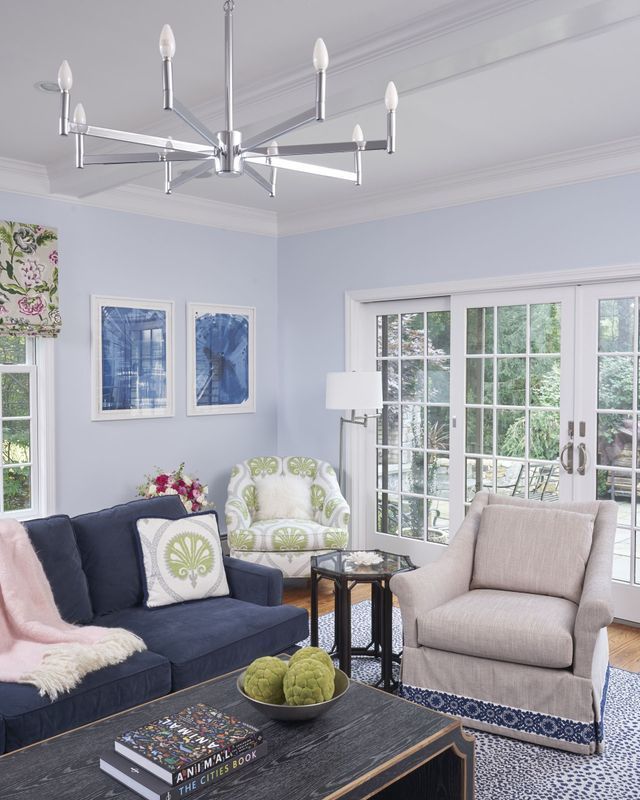 Living room with blue sofa, two armchairs, and a modern chandelier.