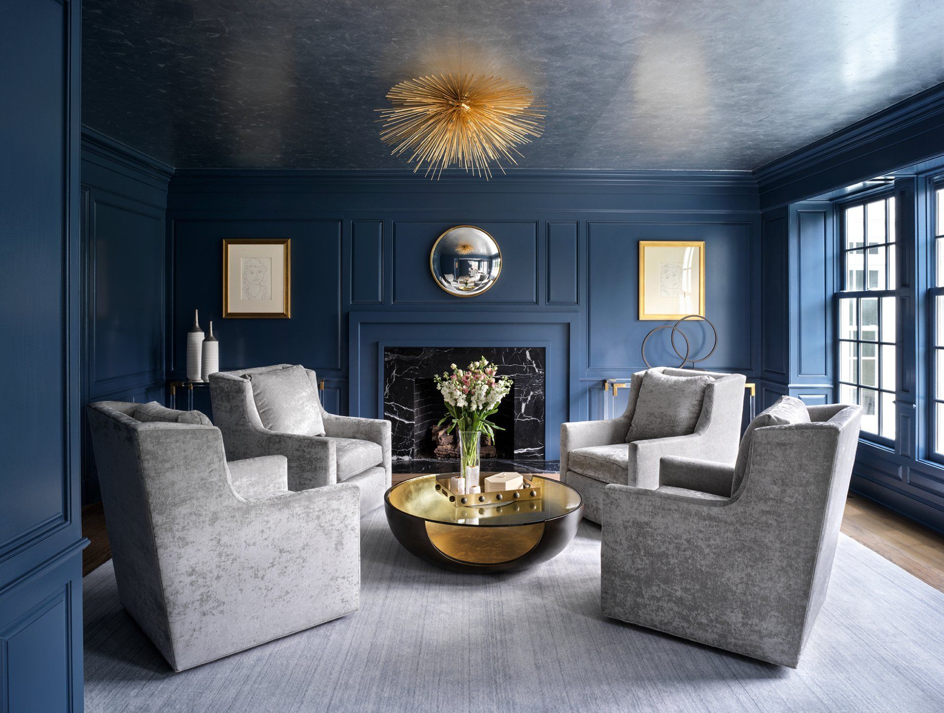 Blue living room with gray chairs, gold light fixture, and metallic ceiling.