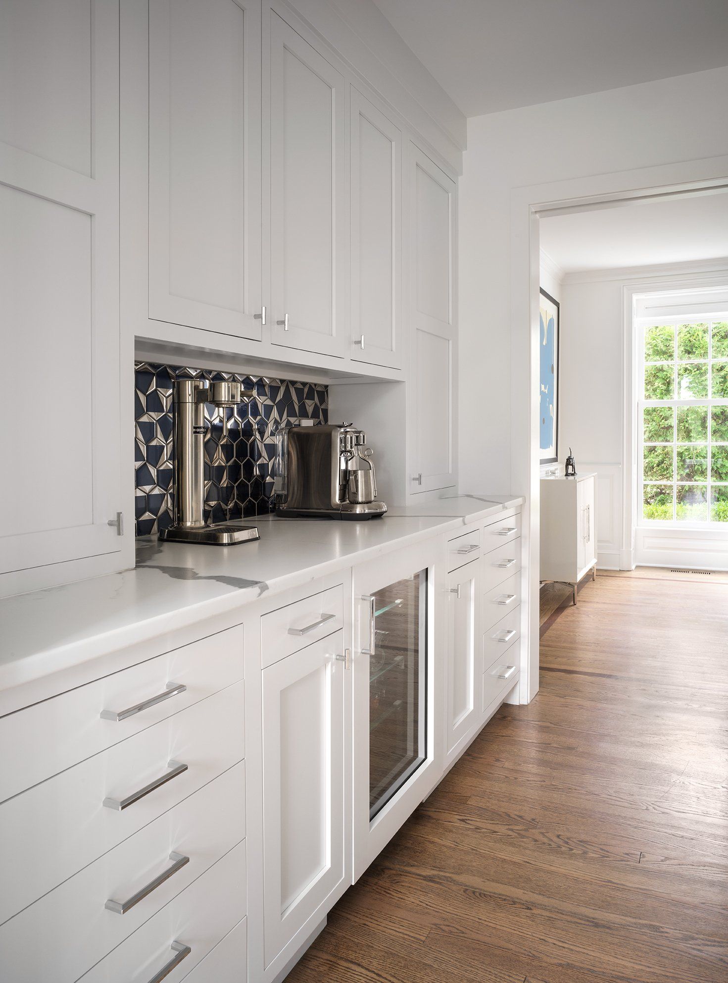 White kitchen cabinetry with built-in appliances and a patterned backsplash.