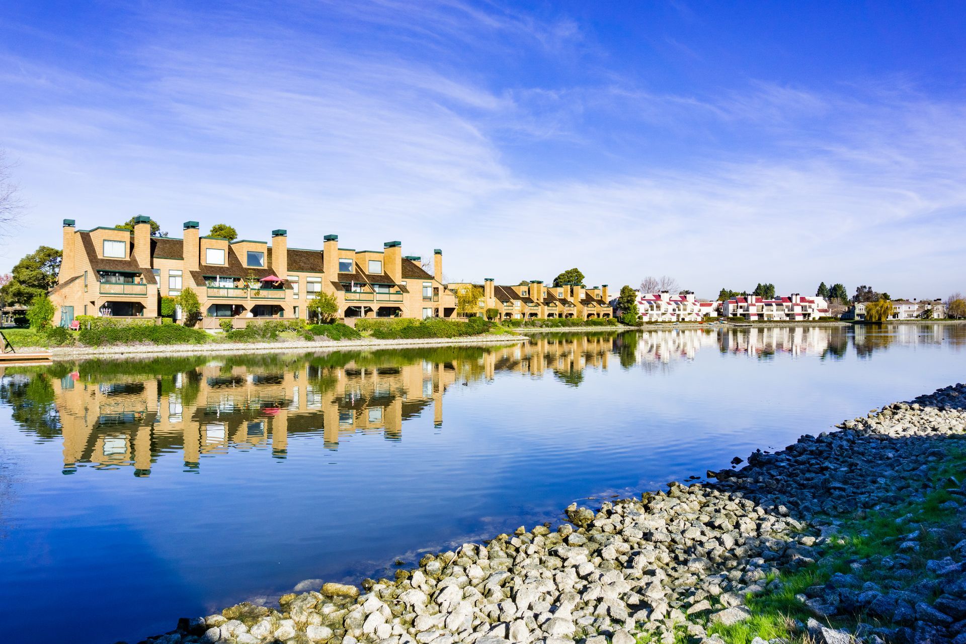A lake with houses on the shore and buildings reflected in the water.