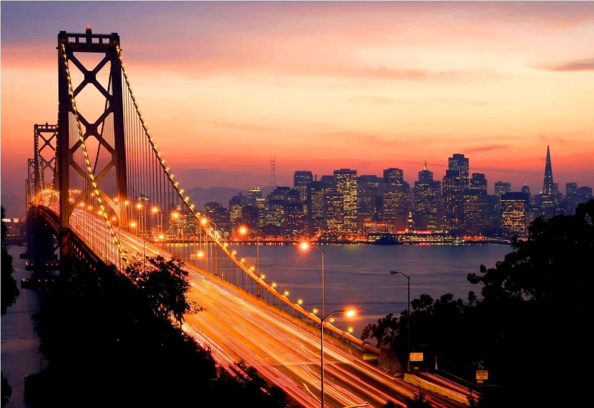 A bridge over a body of water with a city in the background