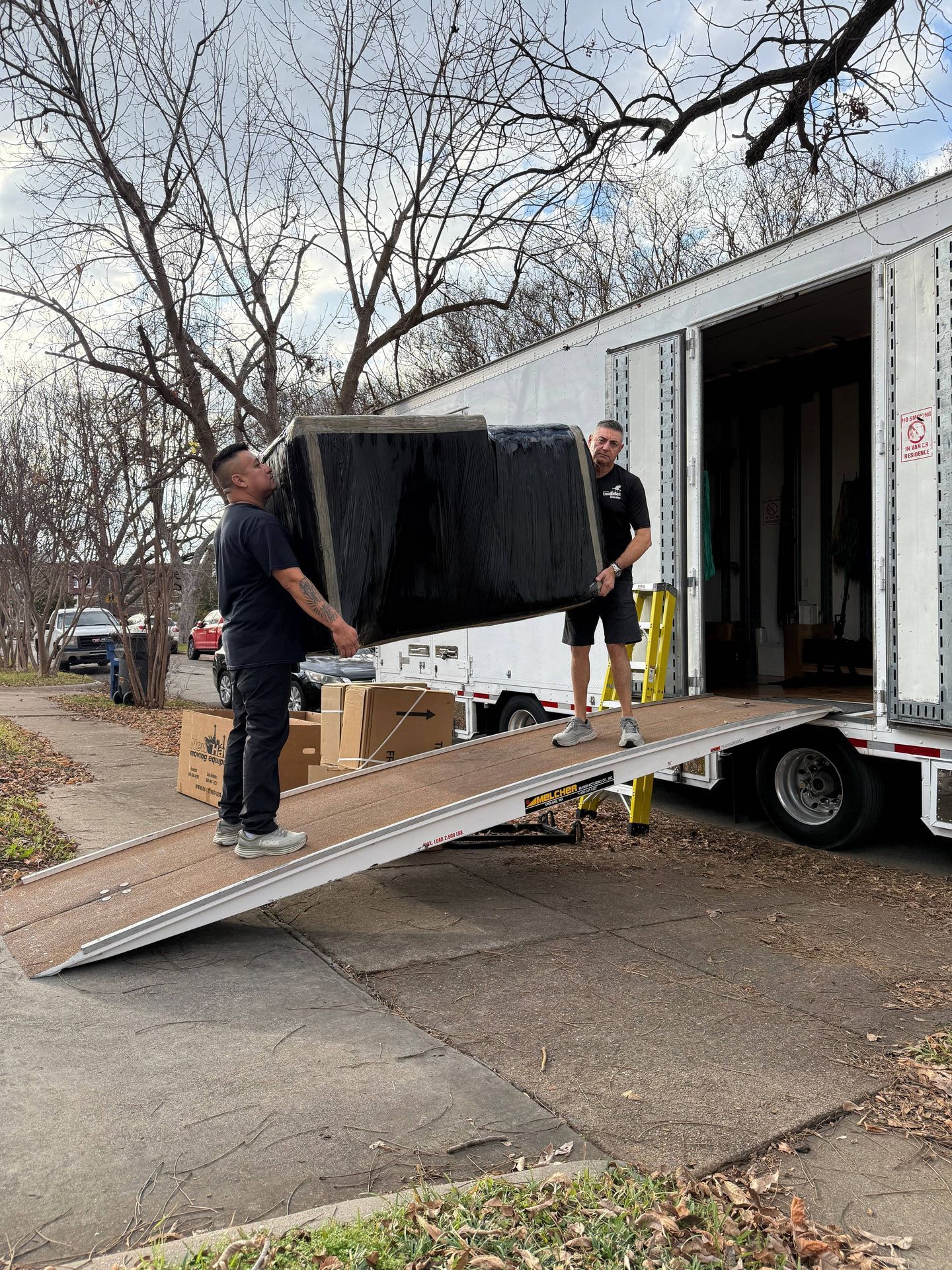 Two men are loading a flat screen tv into a moving truck.