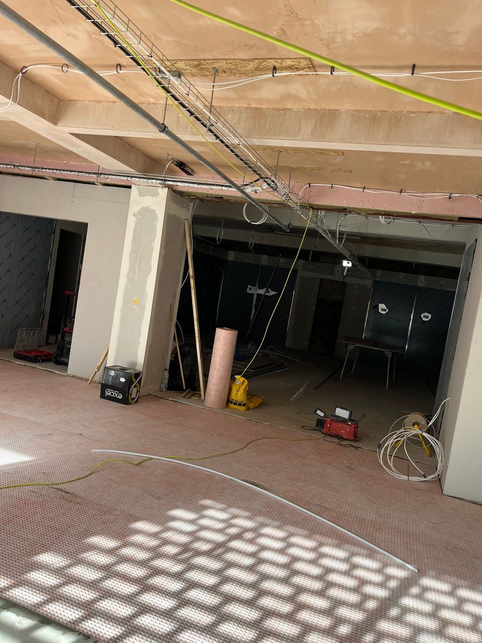 Partially finished room with exposed ceiling, hanging wires, and tools on the floor