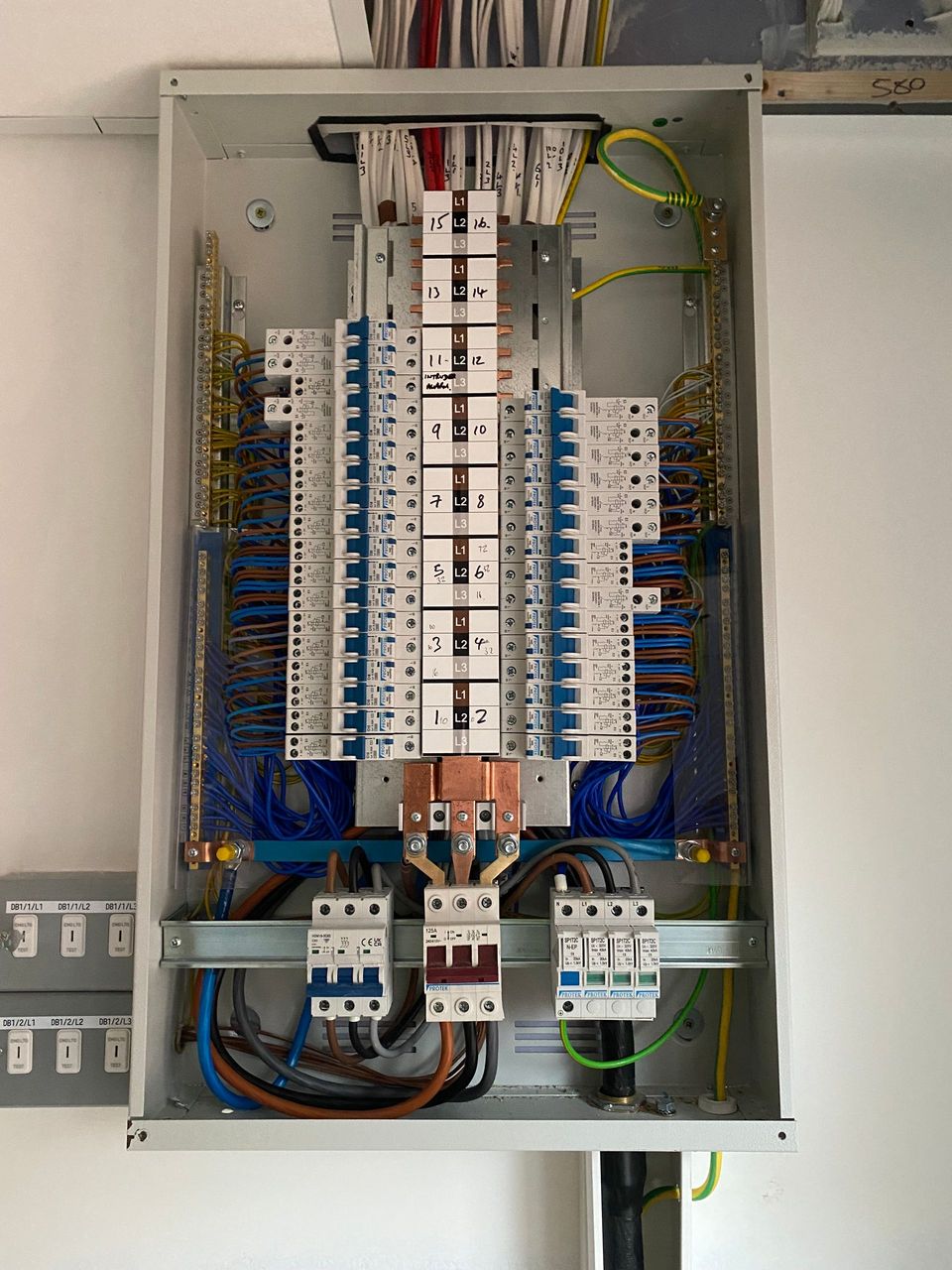 Open electrical control panel with rows of white circuit breakers and blue wiring.