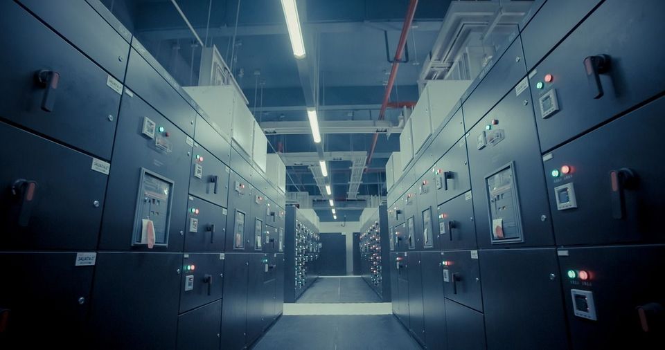Dim server room aisle with tall black cabinets and bright overhead lights