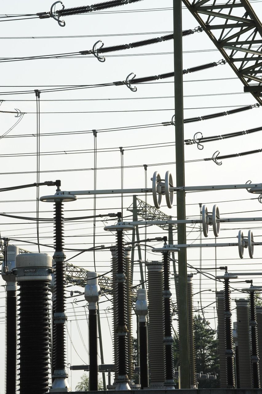 Electrical substation with many power lines and transformers under a bright sky