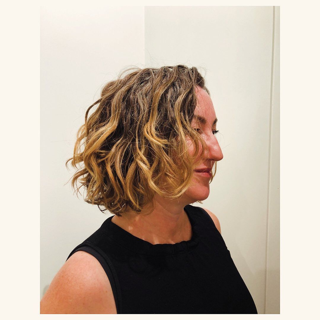 A woman with curly hair is wearing a black tank top
