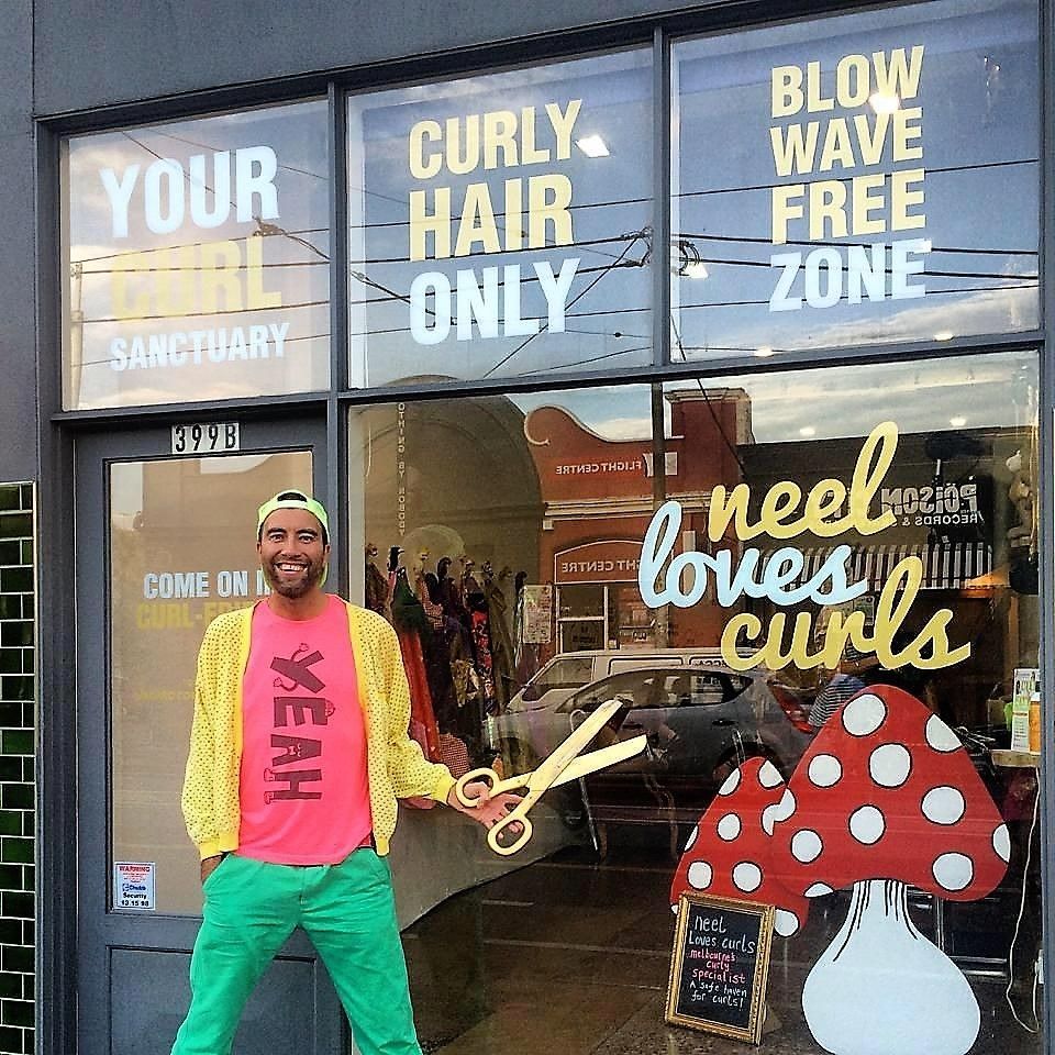 A man standing in front of a store that says curly hair only