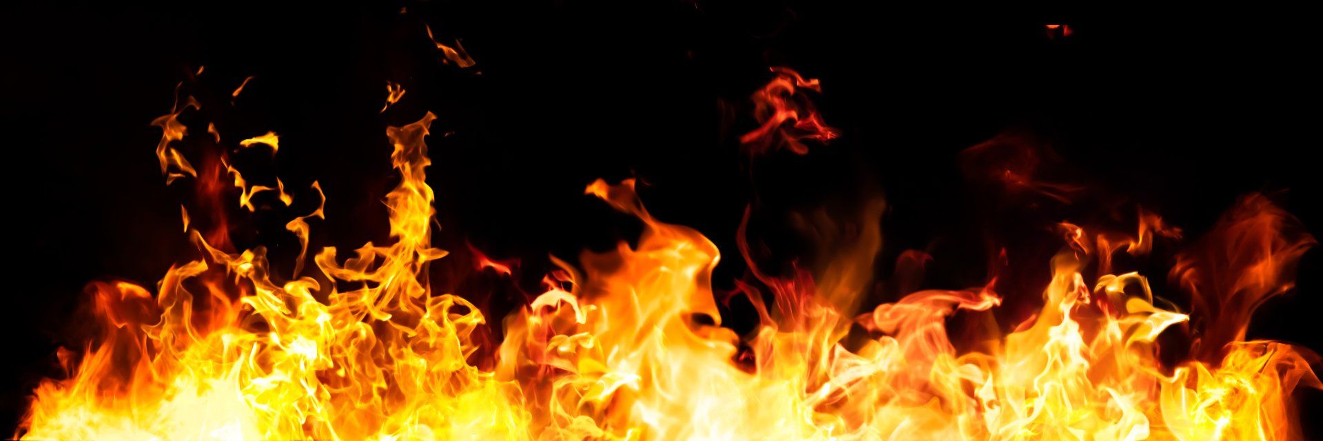 Des flammes aux teintes jaunes et oranges brûlent vivement sur un fond noir.