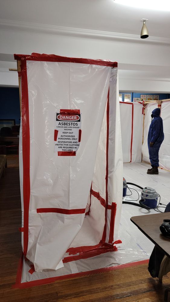 A man in a blue suit is standing behind a white tarp in a room.