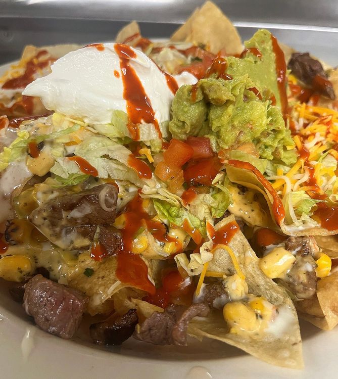 A close up of a plate of nachos with guacamole and cheese