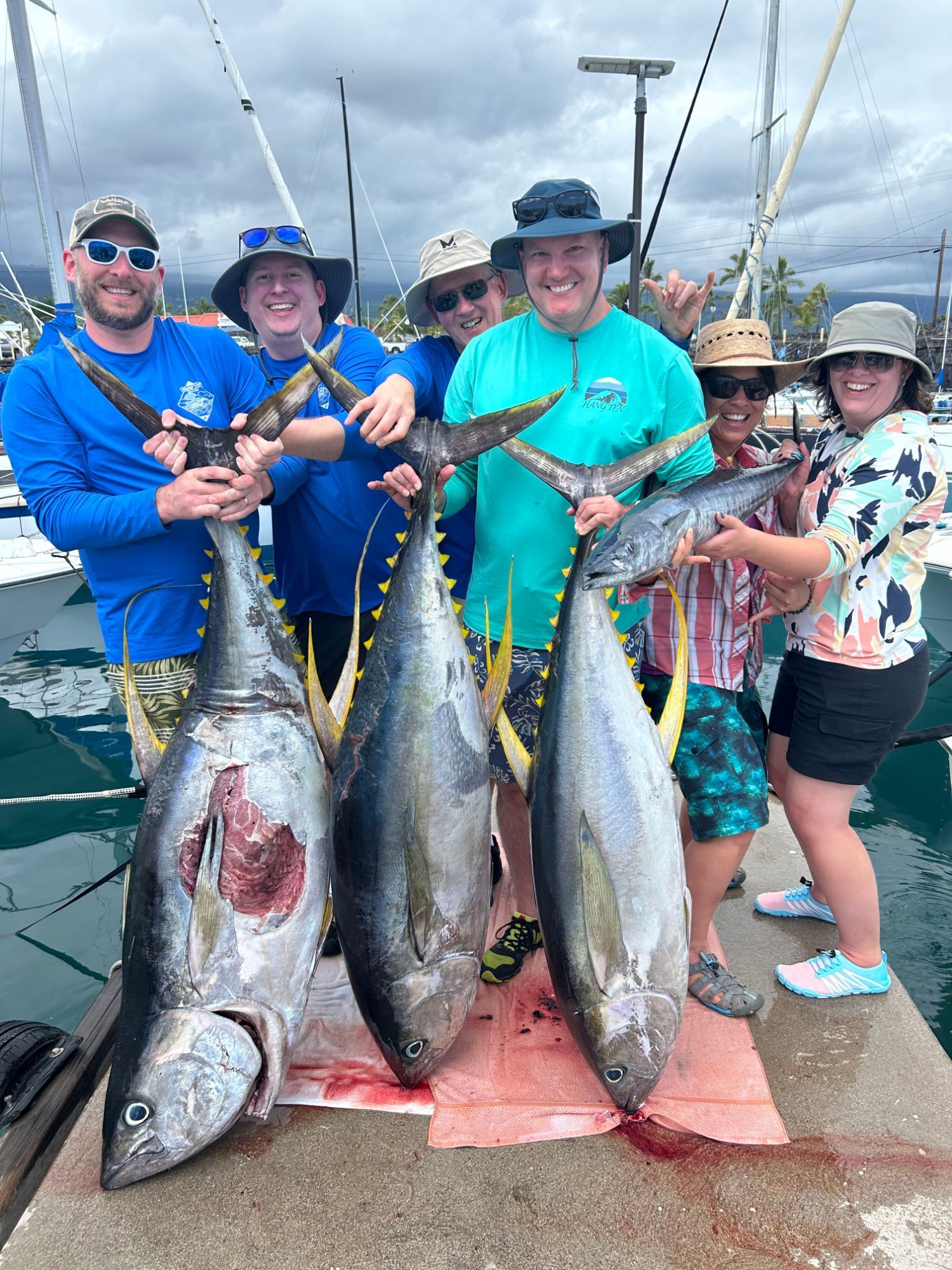 A group of people standing next to each other holding fish