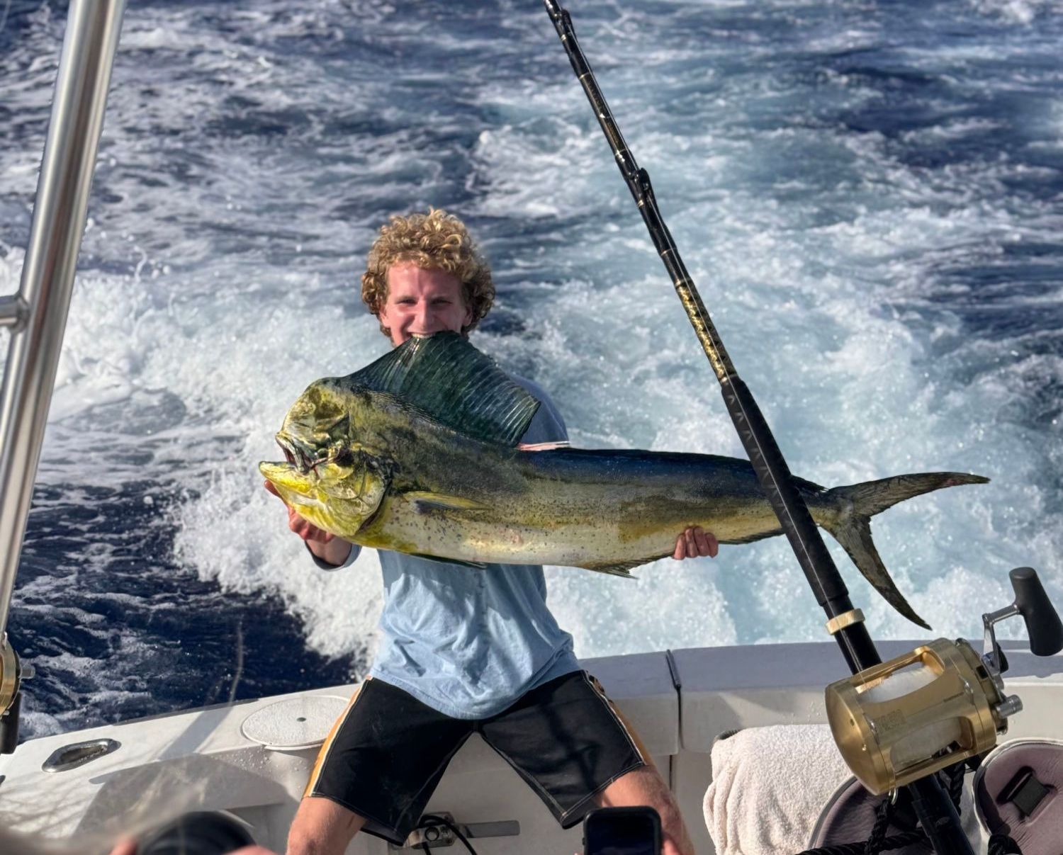 A man is holding a large fish on a boat