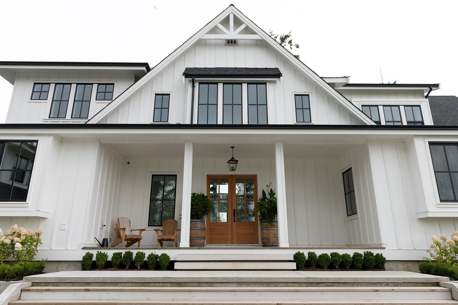 Large white house with a gabled roof, front porch, and steps leading to wooden double doors Large white house with a gabled roof, front porch, and steps leading to wooden double doors