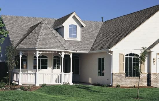 Suburban house with gray roof, white siding, and a small front porch under a blue sky