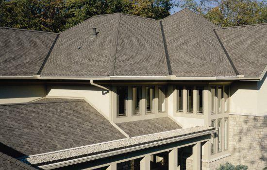 Exterior of a house with gray shingled roof and rows of narrow windows