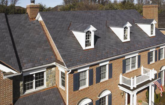 Worker installing red roof tiles on a house under a blue sky
