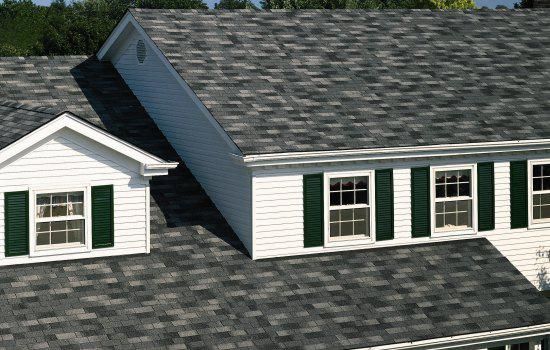 White house roof with gray shingles and dormer windows with green shutters