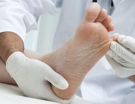 Un médico está examinando el pie de un paciente con guantes puestos.