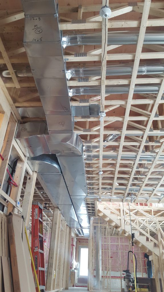 Un grand conduit est suspendu au plafond d'un bâtiment en construction.