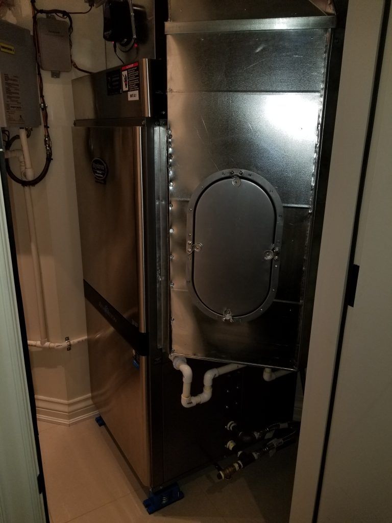 Un réfrigérateur se trouve dans une pièce à côté d'une porte.