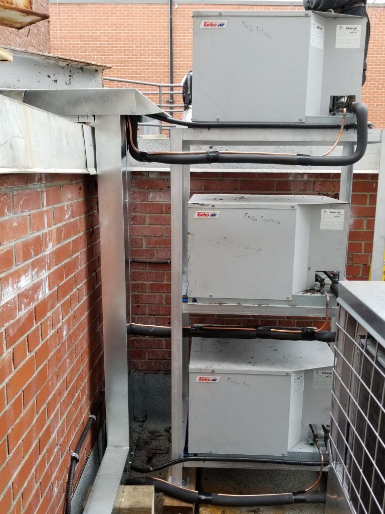 Une rangée de boîtes blanches sont empilées les unes sur les autres devant un mur de briques.