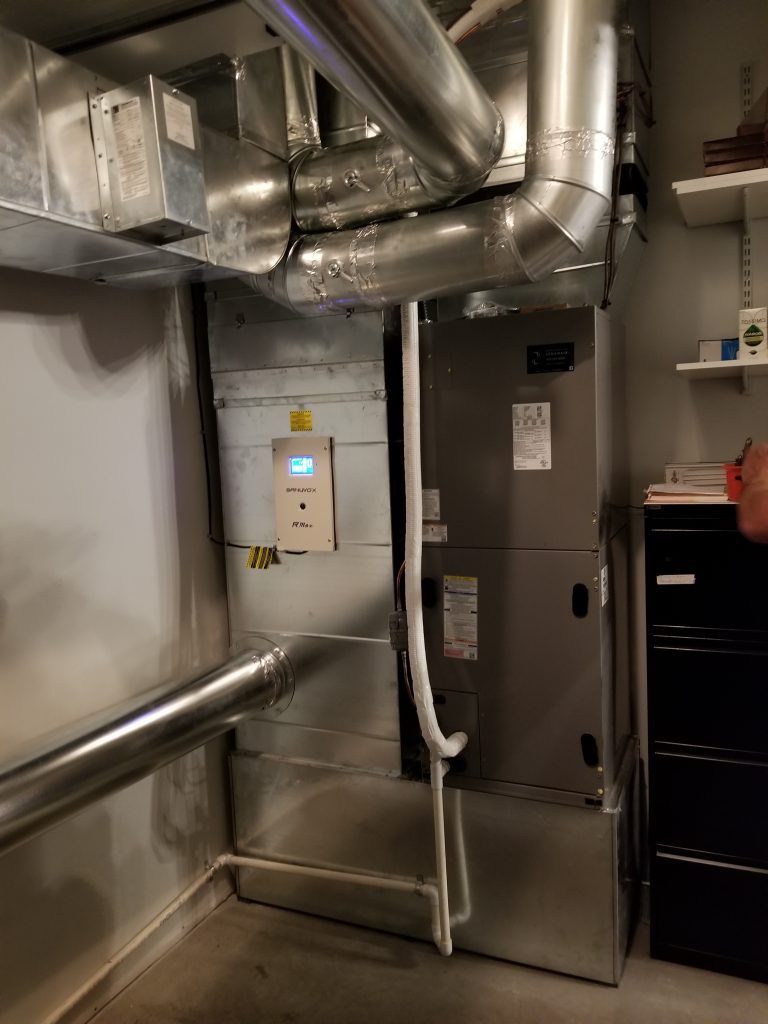 Une pièce avec un radiateur et des tuyaux suspendus au plafond.