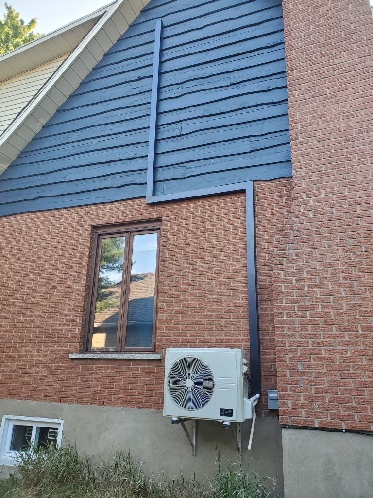 Une maison en brique avec une fenêtre et un climatiseur sur le côté.