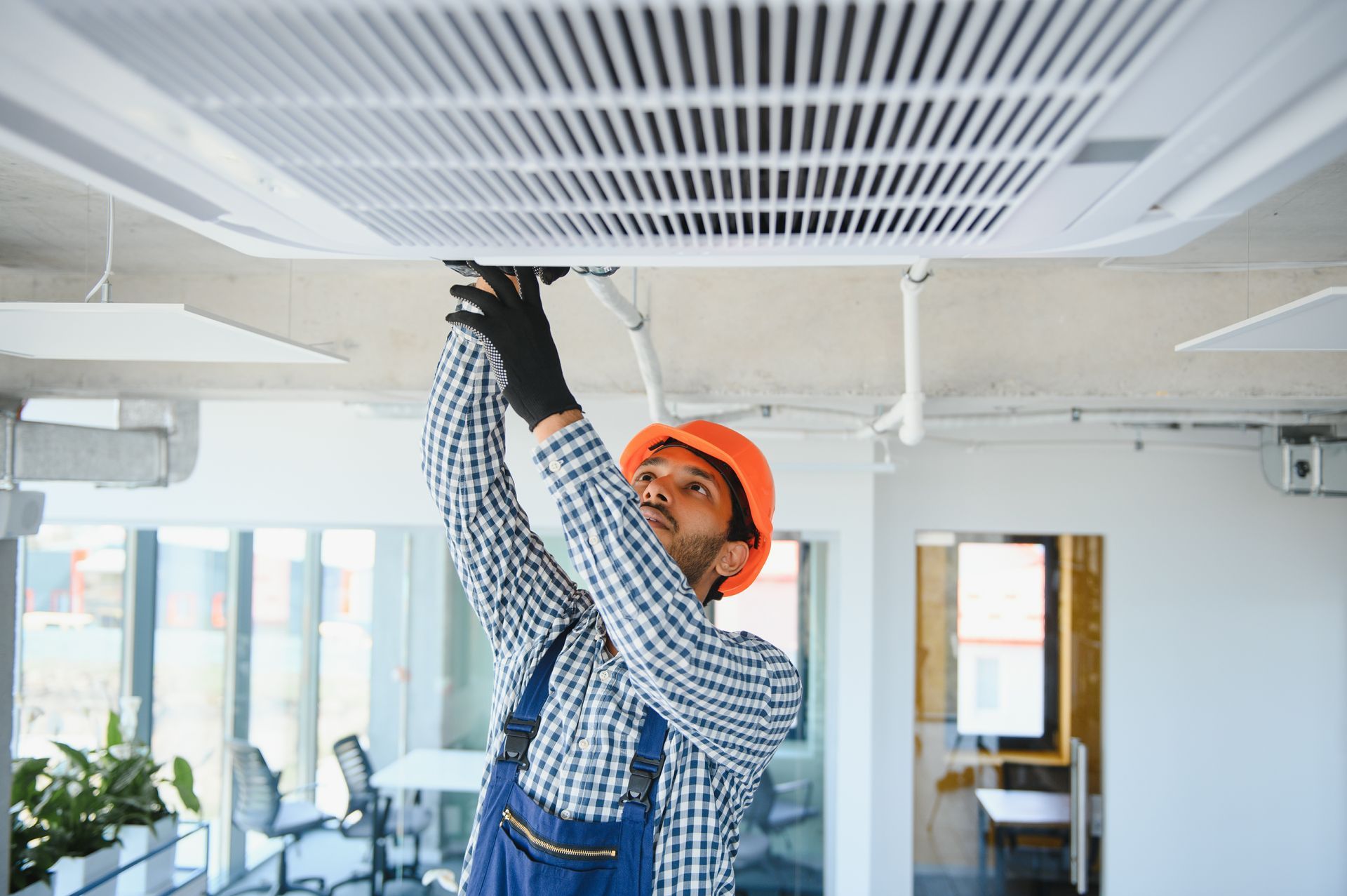 Un homme travaille sur un ventilateur de plafond dans un bureau.