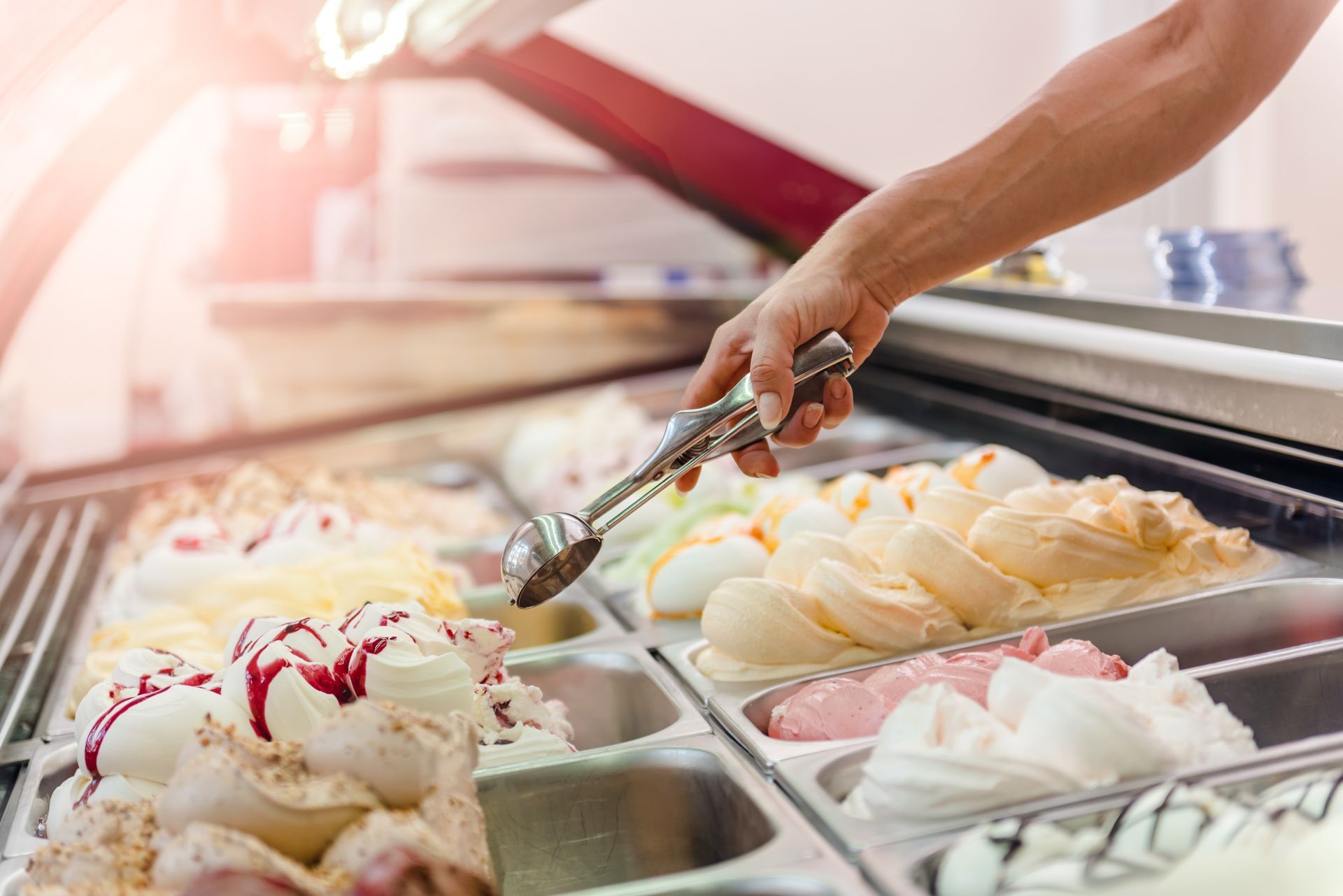Une personne prend de la glace dans une vitrine avec des pinces.