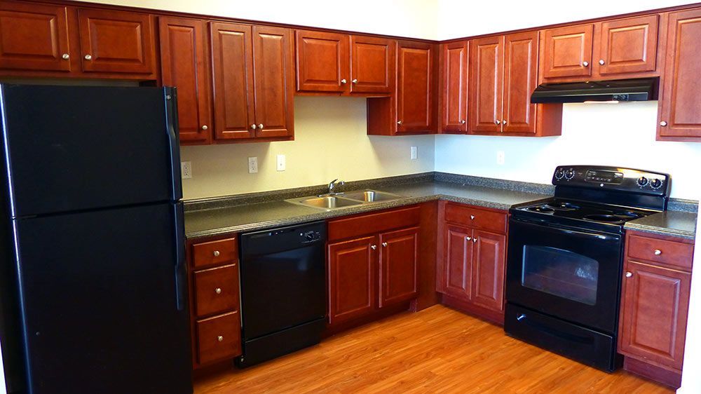 Modern kitchen with dark wood cabinets, black appliances, and wood flooring