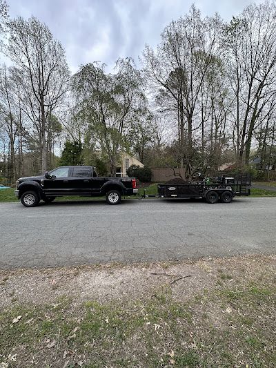 A black truck with a trailer attached to it is parked on the side of the road.