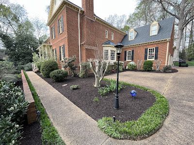 A large brick house with a large driveway and a walkway leading to it.