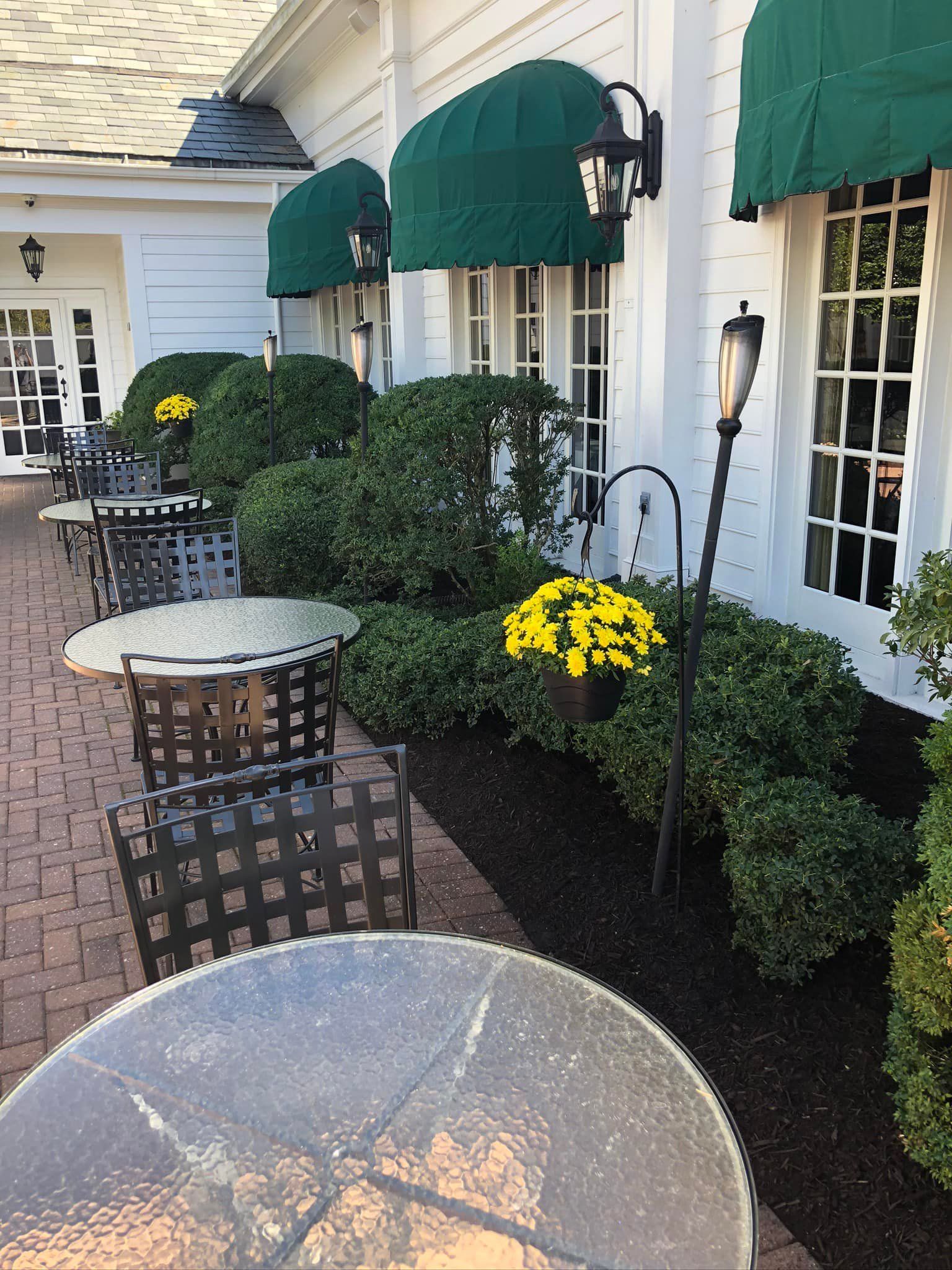 A patio with tables and chairs under green awnings
