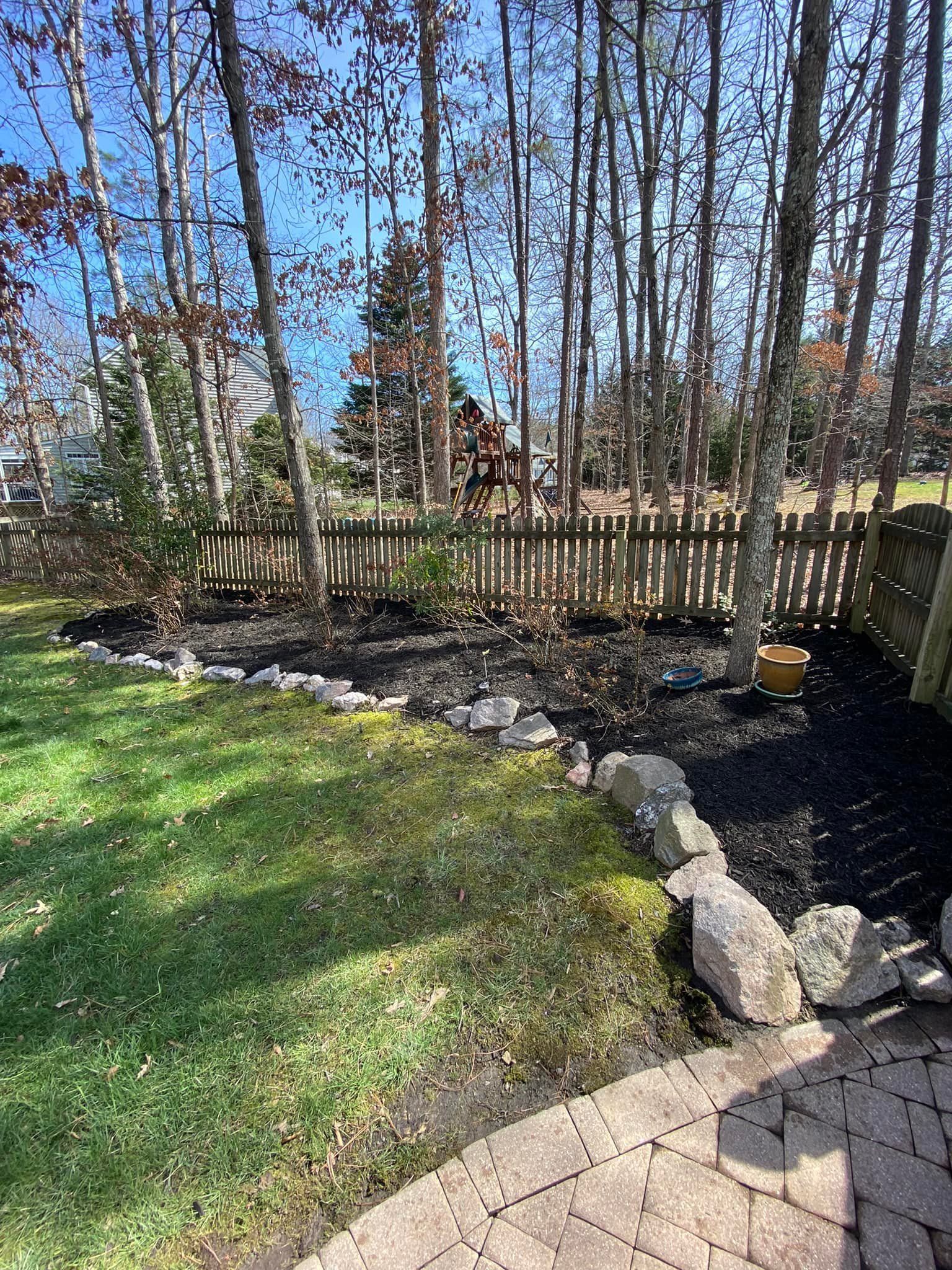 A backyard with a brick patio and trees in the background.