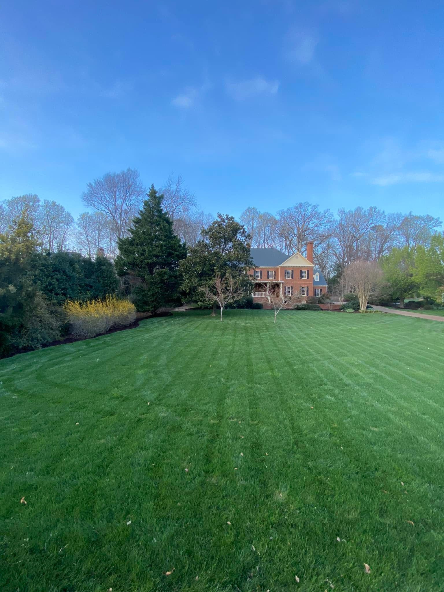 A large lush green field with a brick house in the background.