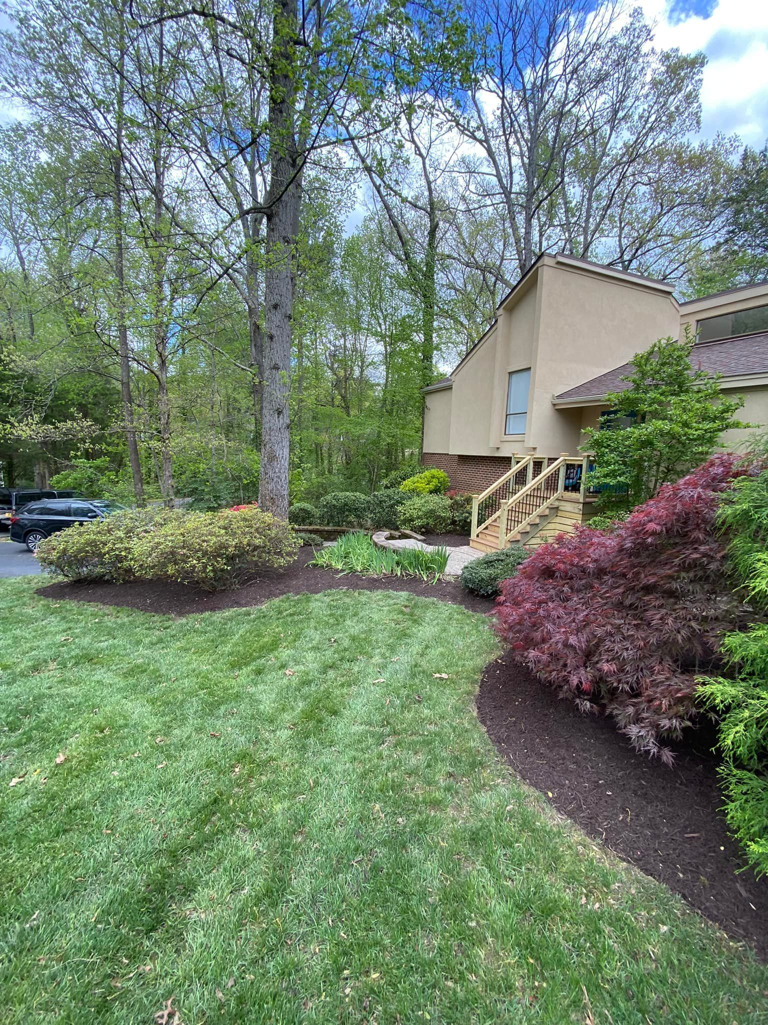A house with a lush green lawn and trees in front of it.