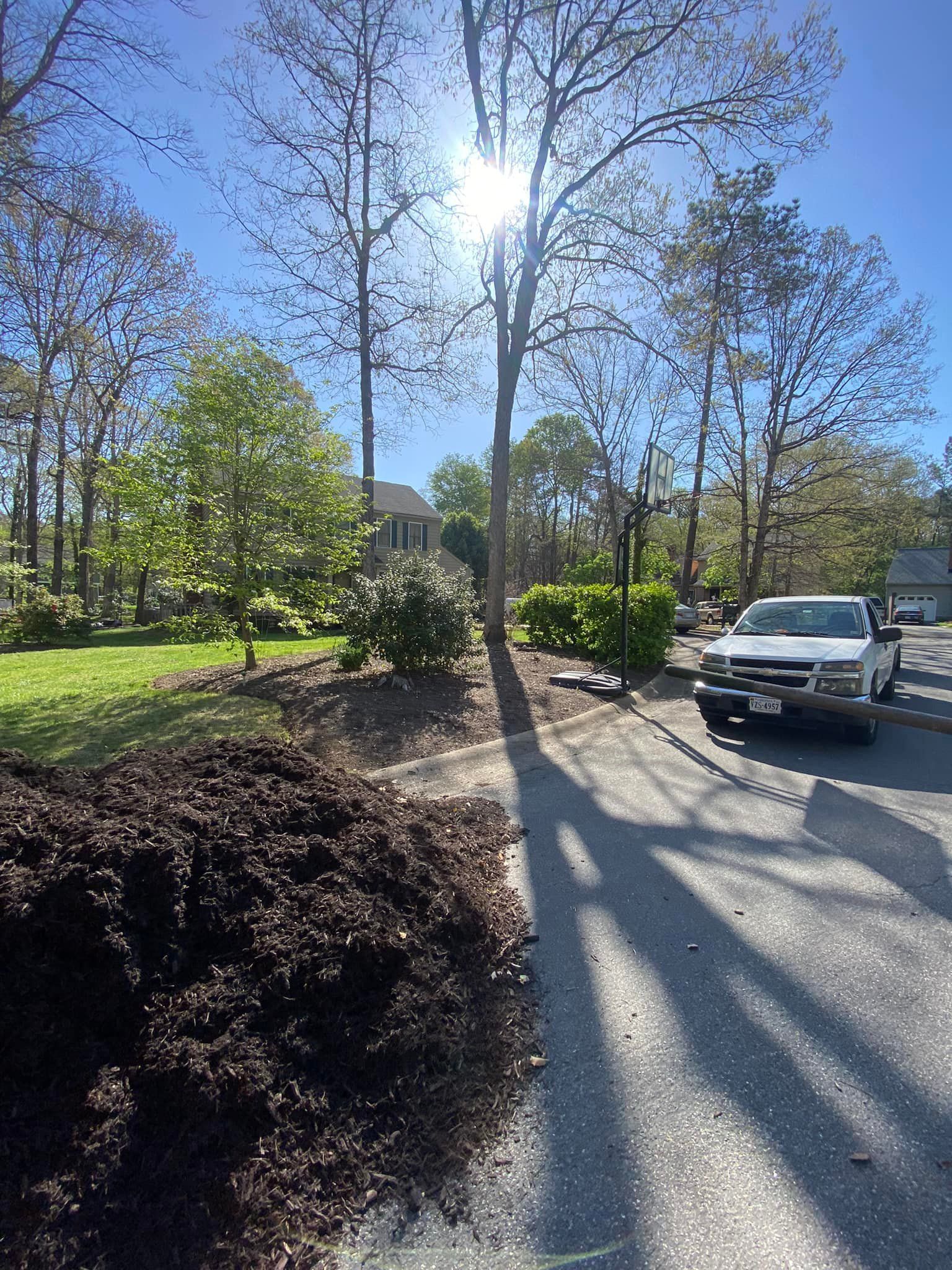 A white truck is parked on the side of the road next to a pile of mulch.