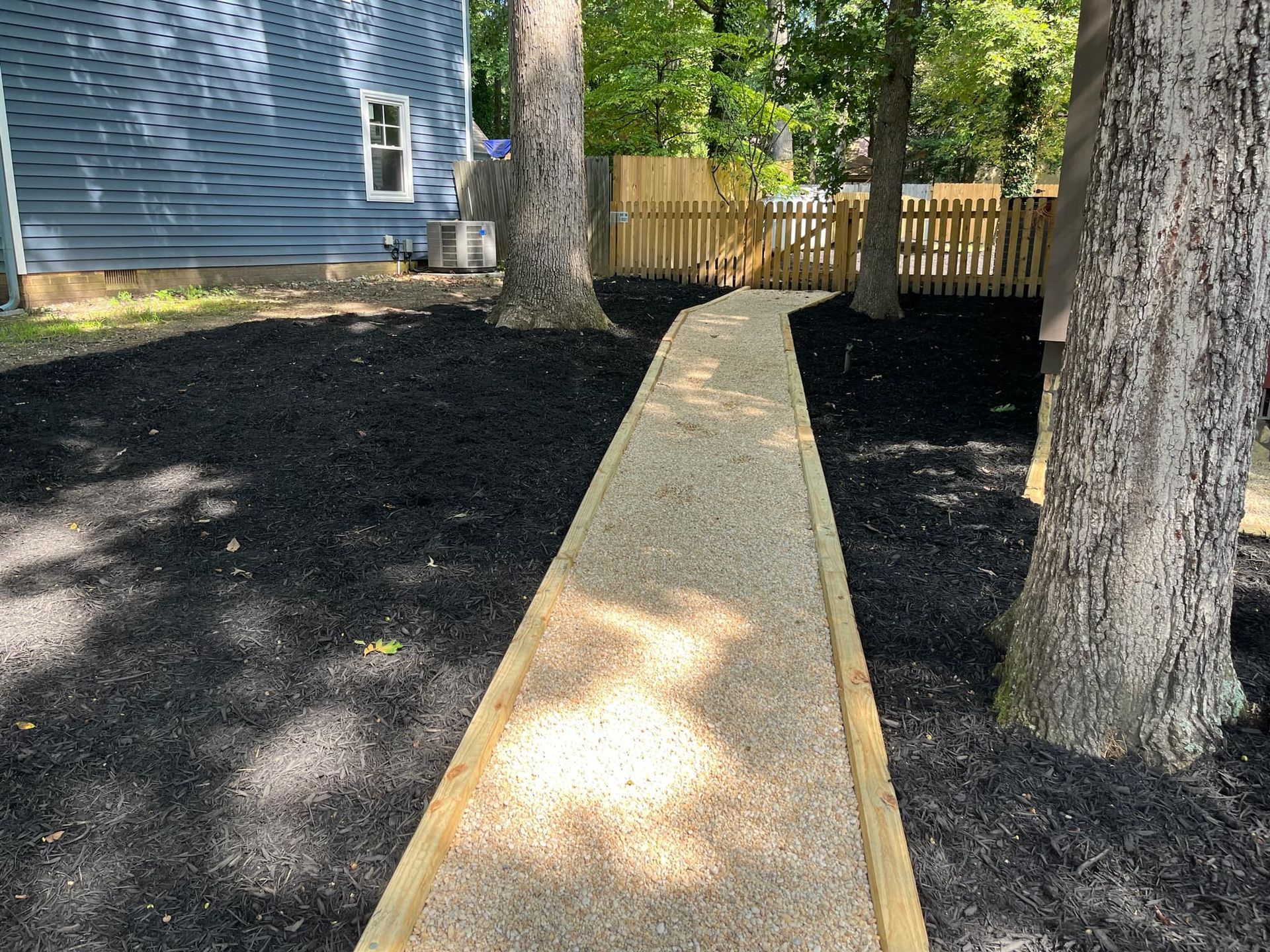A wooden walkway leading to a house surrounded by trees.