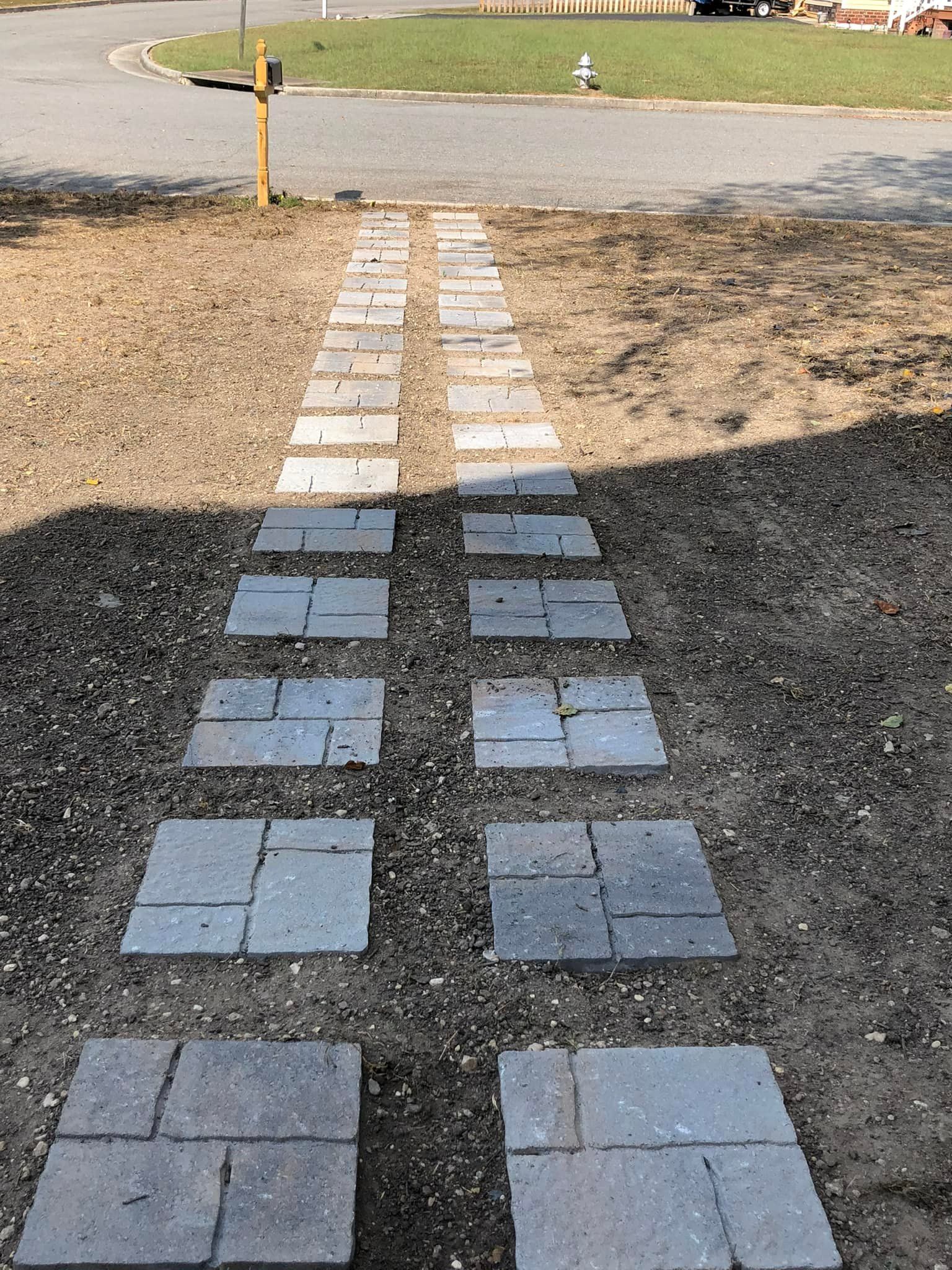 A walkway made of bricks is being built in the dirt.