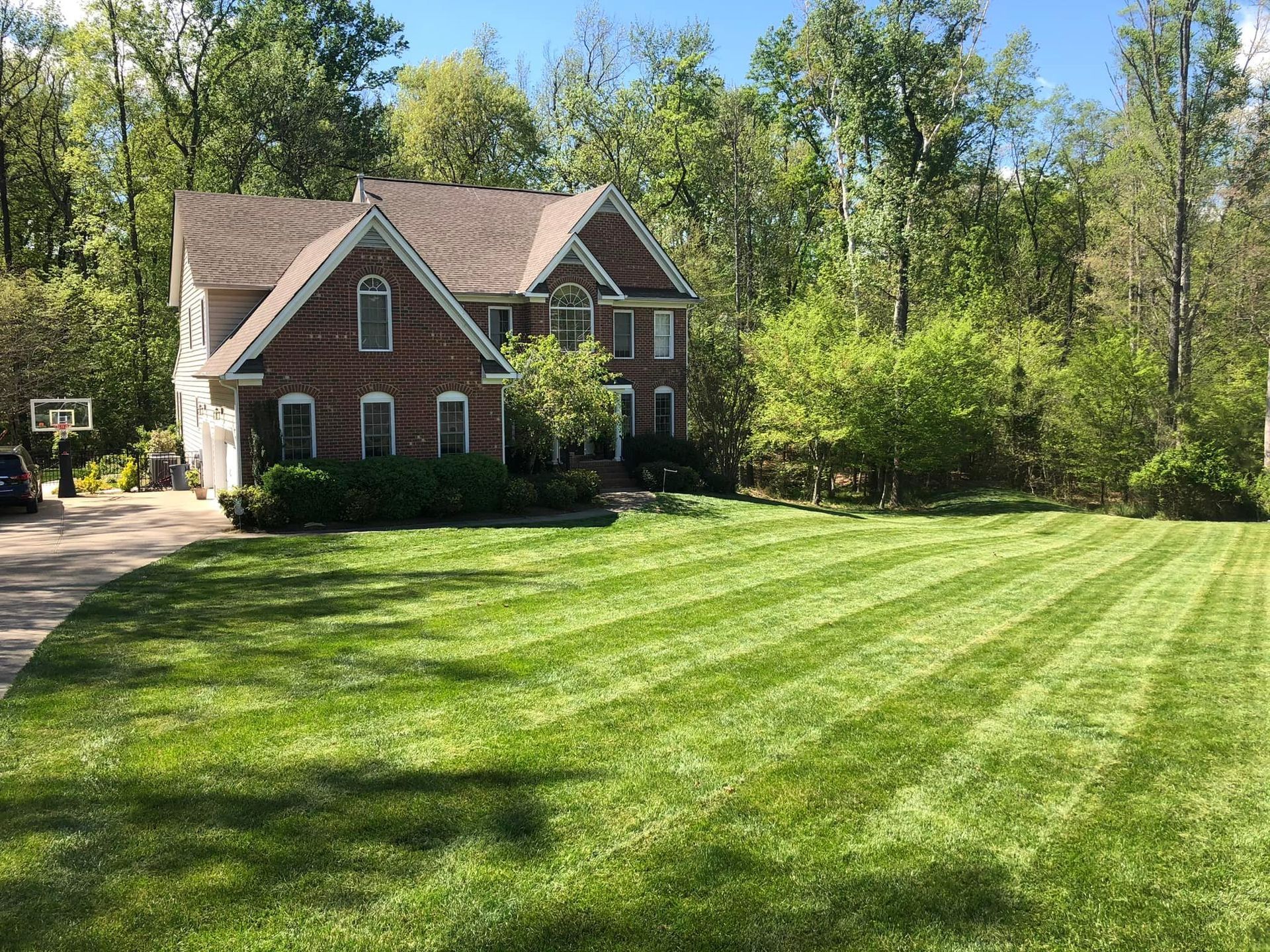 A large brick house with a lush green lawn in front of it.